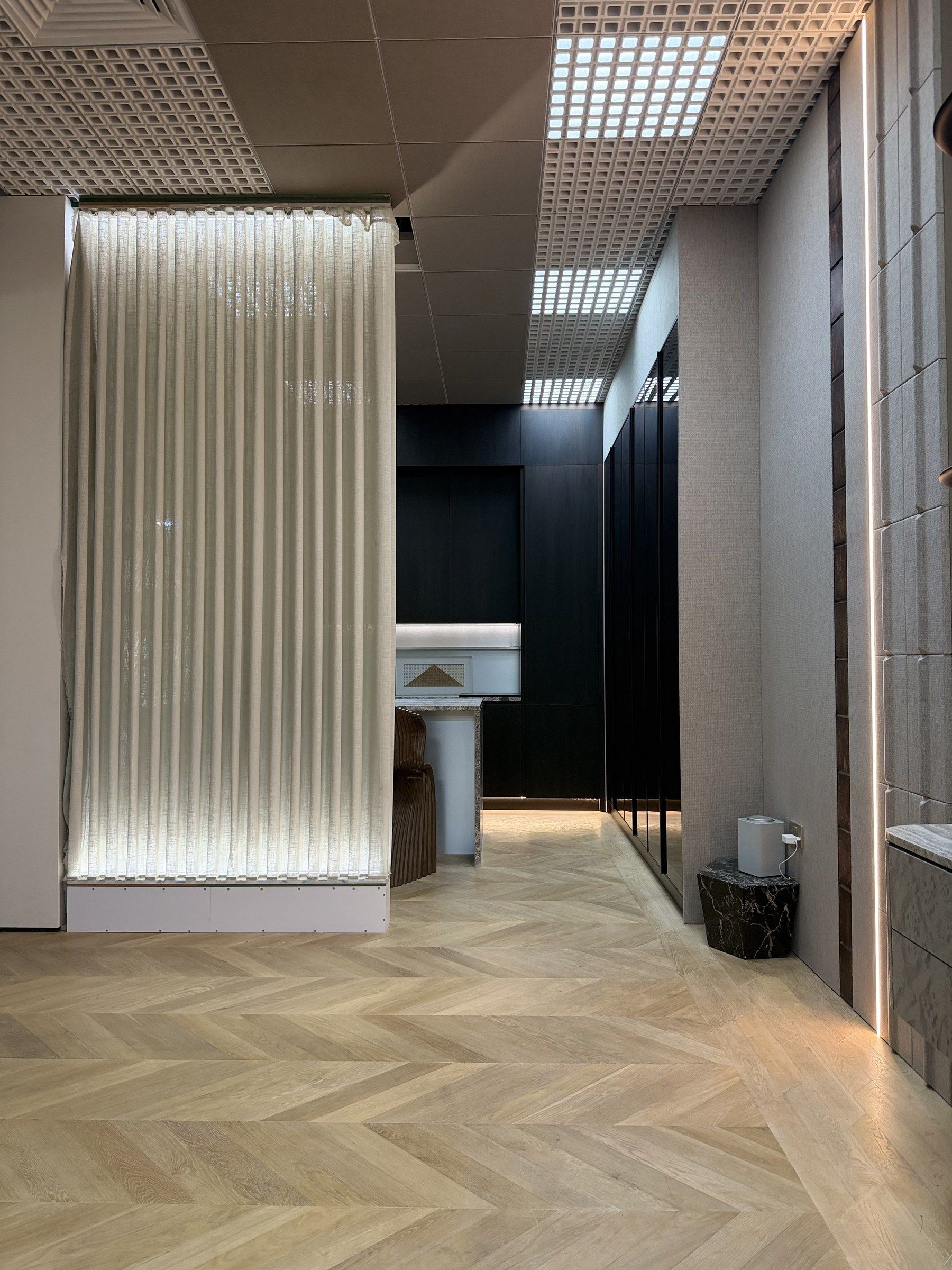 Backlit textile panel beside a dark joinery wall