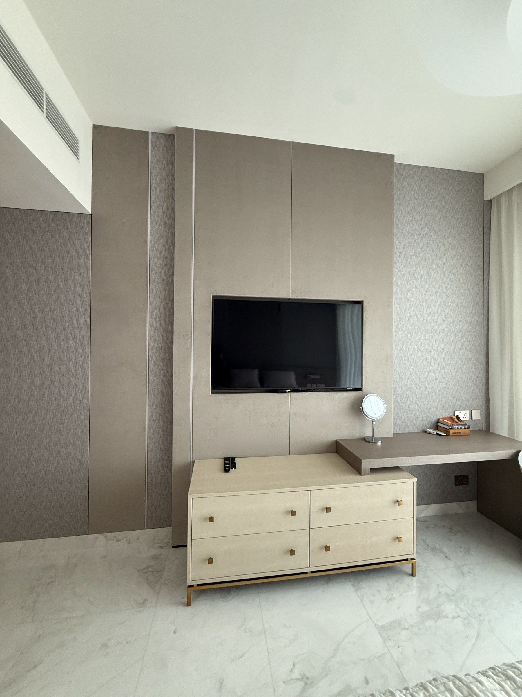 Bedroom wall in fabric panels with a built-in desk and TV