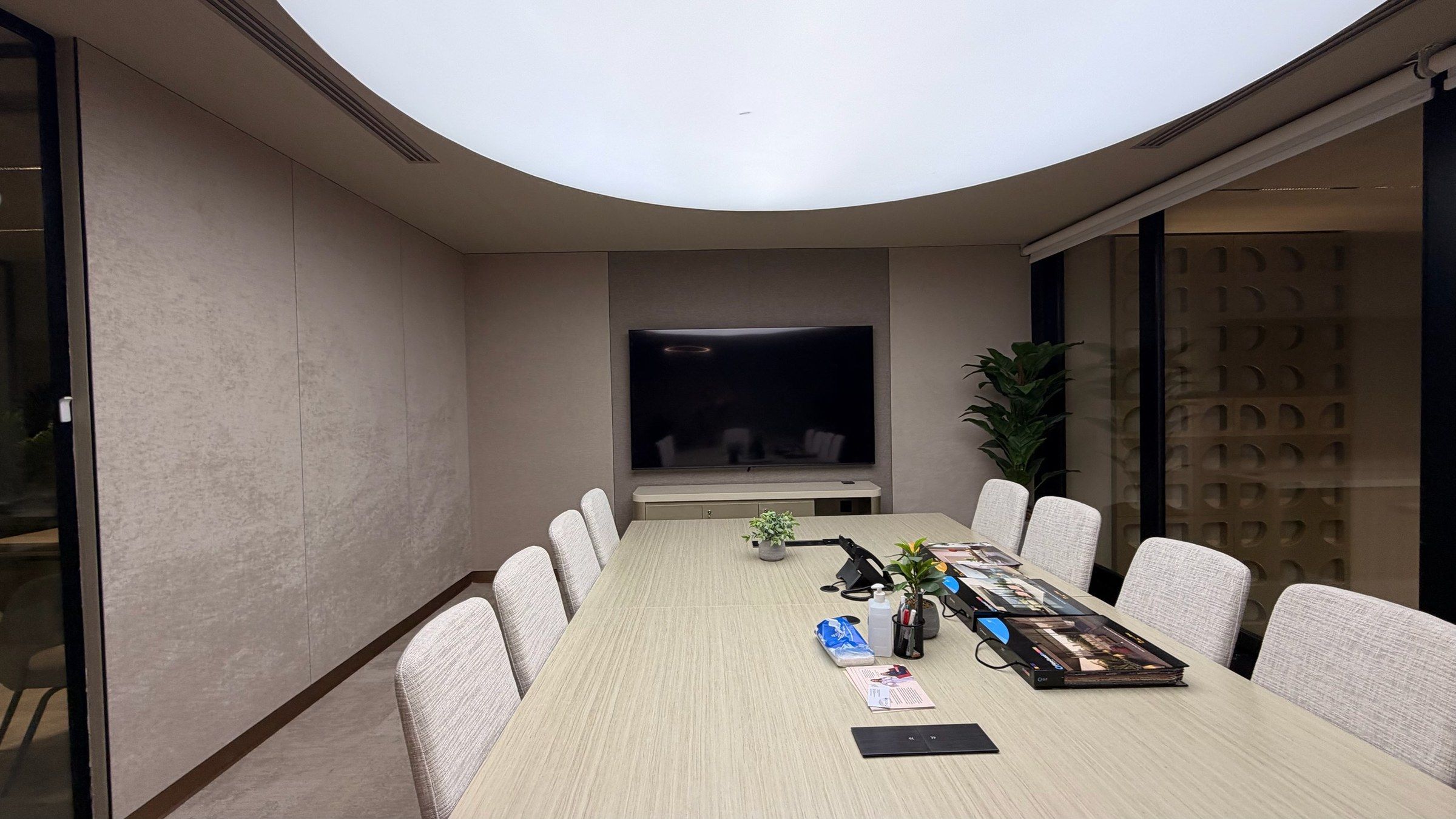 Meeting room with textile walls, a long table and a backlit ceiling