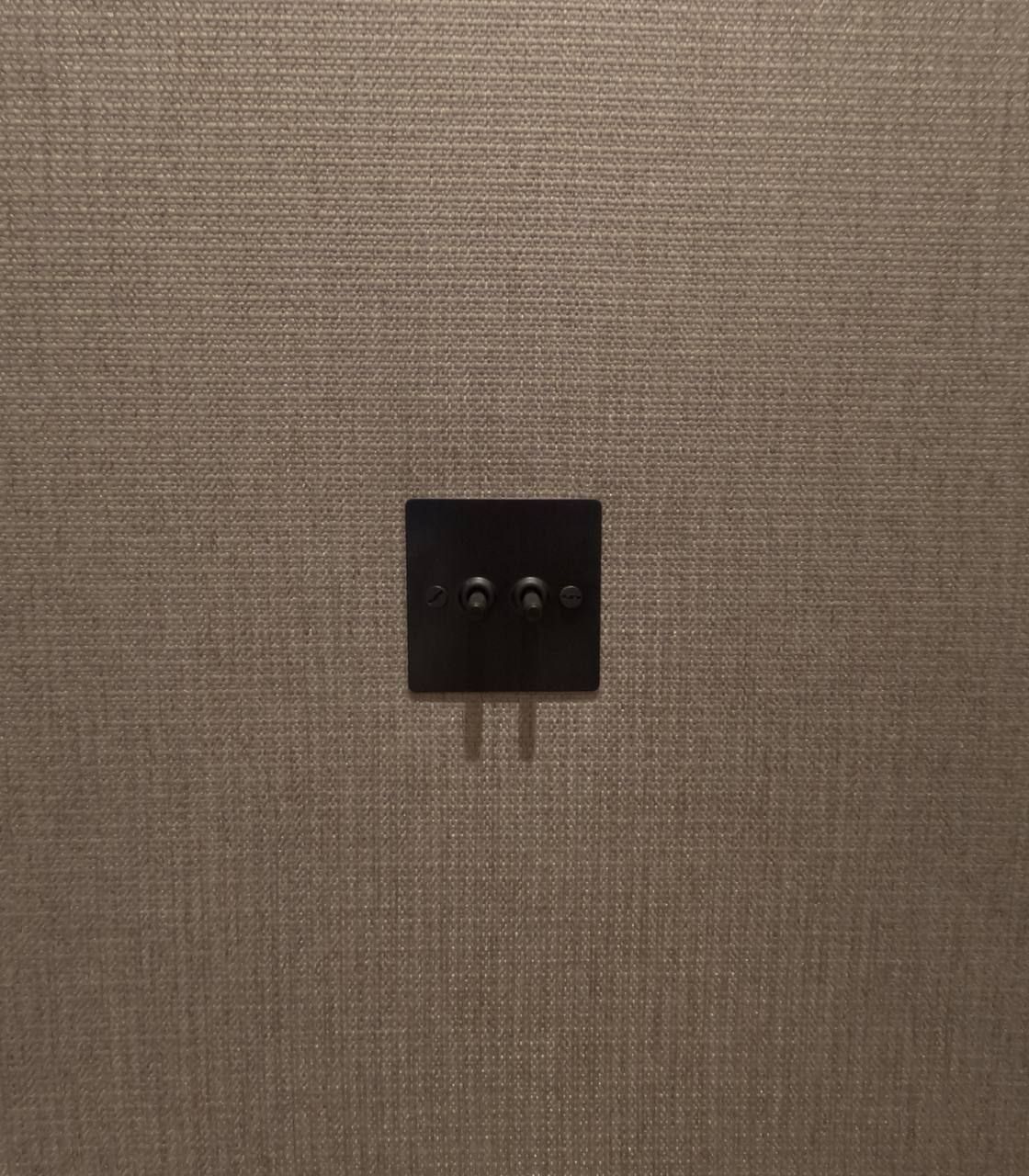 Bronze switch set flush into an upholstered textile wall